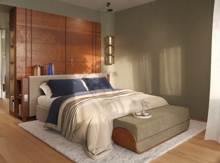 Bedroom with a beige upholstered bed, navy pillows, and a large wood panel headboard against a tan wall; pendant light and ottoman at the foot.