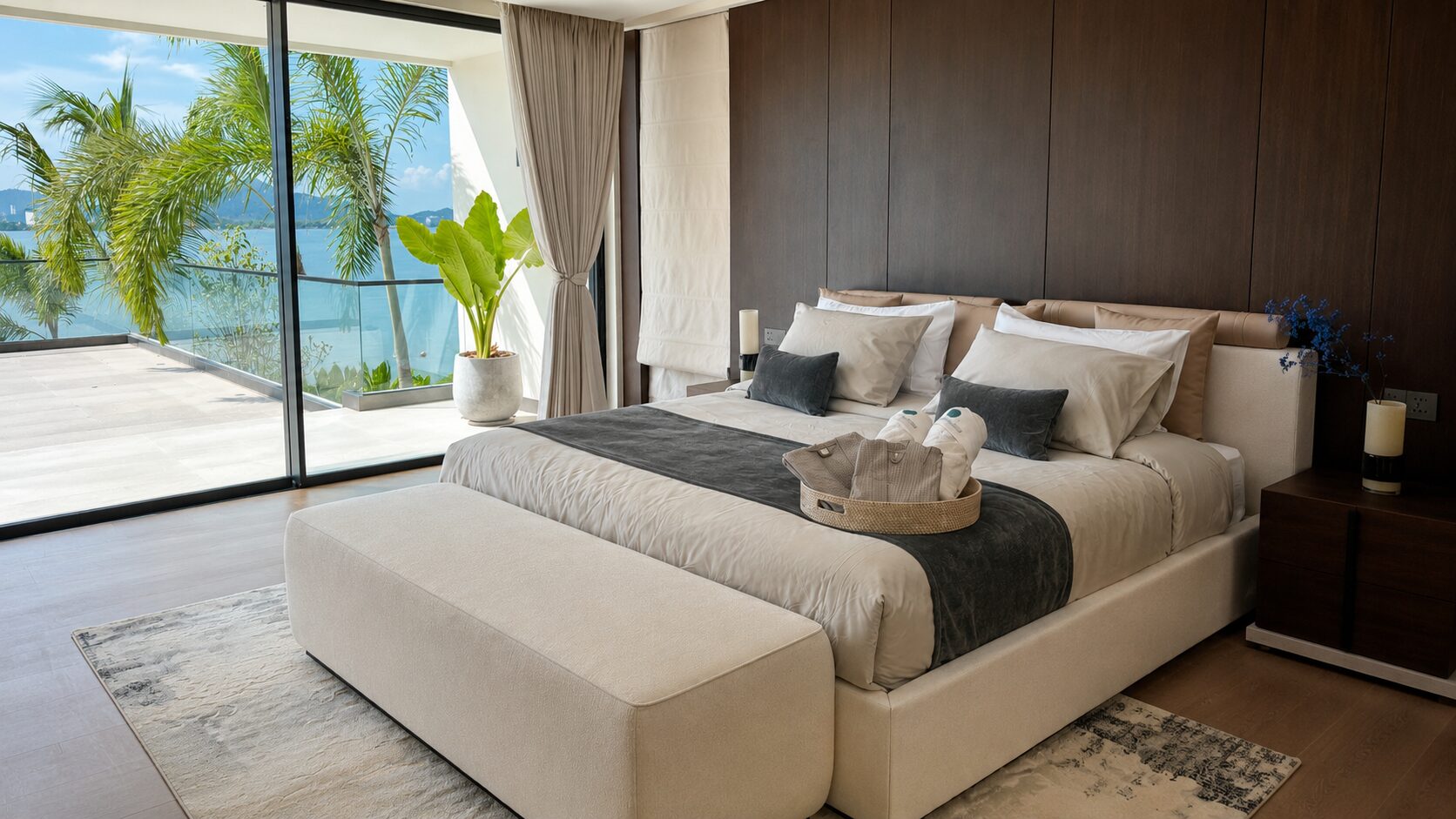 Luxurious bedroom with a king bed, beige upholstery, and a balcony view of palm trees and the sea.