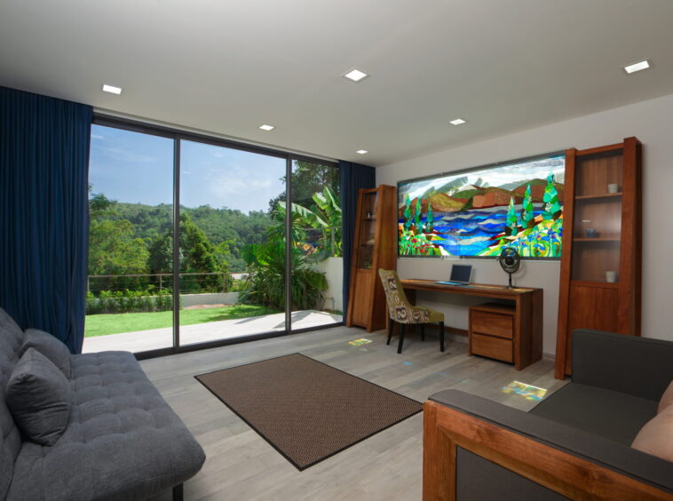 Living room with large glass sliding doors opening to a green lawn and trees, blue curtains frame the view.