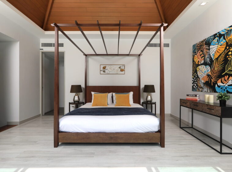 Modern bedroom with a dark wood four-poster bed, white bedding, and yellow accent pillows; brown lamps on each side.