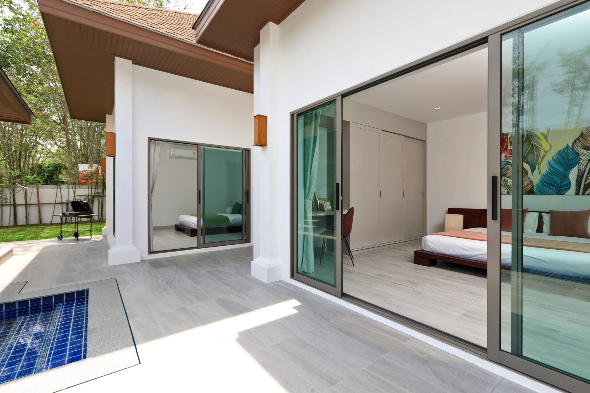 Patio with light gray tiles, pool nearby, and large glass doors opening to a sunlit bedroom.