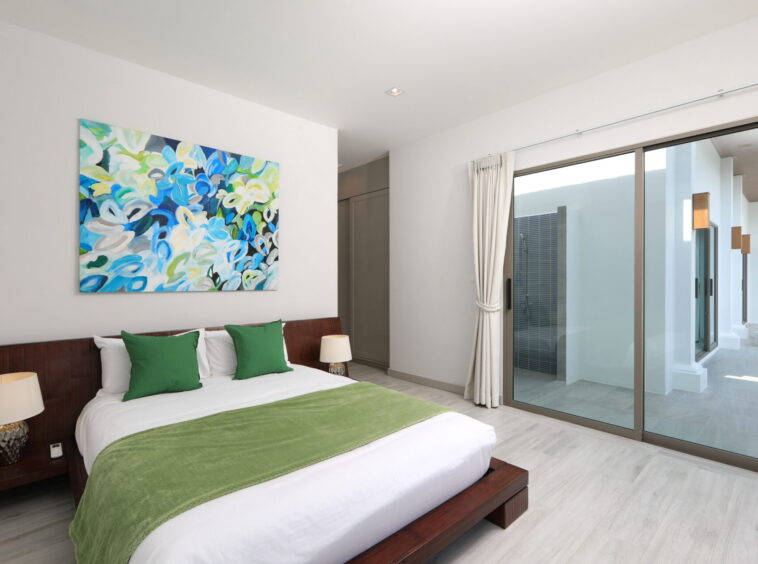 Hotel bedroom with white linens, green throw pillows, and a dark wooden bed frame.
