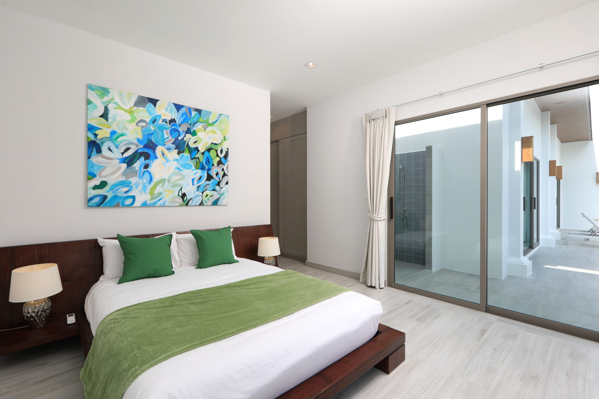 Hotel bedroom with white linens, green throw pillows, and a dark wooden bed frame.