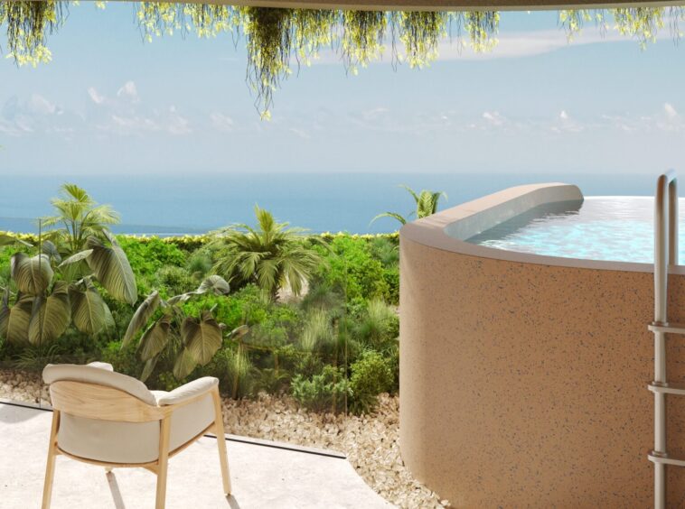 Patio with a beige chair and sandals, overlooking a tropical garden and the blue ocean beyond at sunset light.