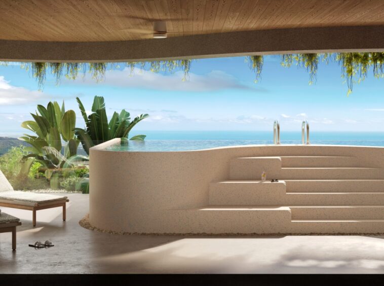 Open-air pool area with curved beige wall, steps, and ocean view beyond, lounge chairs and tropical plants nearby under a wooden ceiling.