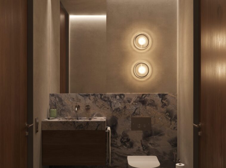 Modern bathroom with marble vanity on left, toilet on right, warm recessed lighting and wood-paneled walls