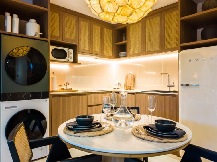 Cozy modern kitchen with a stacked washer and dryer, wooden cabinets, and a cream SMEG fridge.