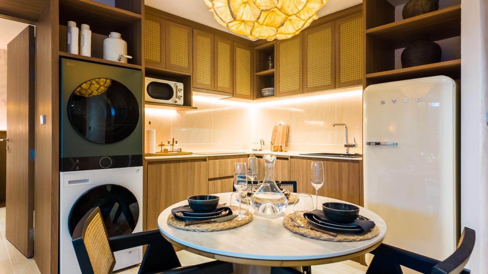 Cozy modern kitchen with a stacked washer and dryer, wooden cabinets, and a cream SMEG fridge.