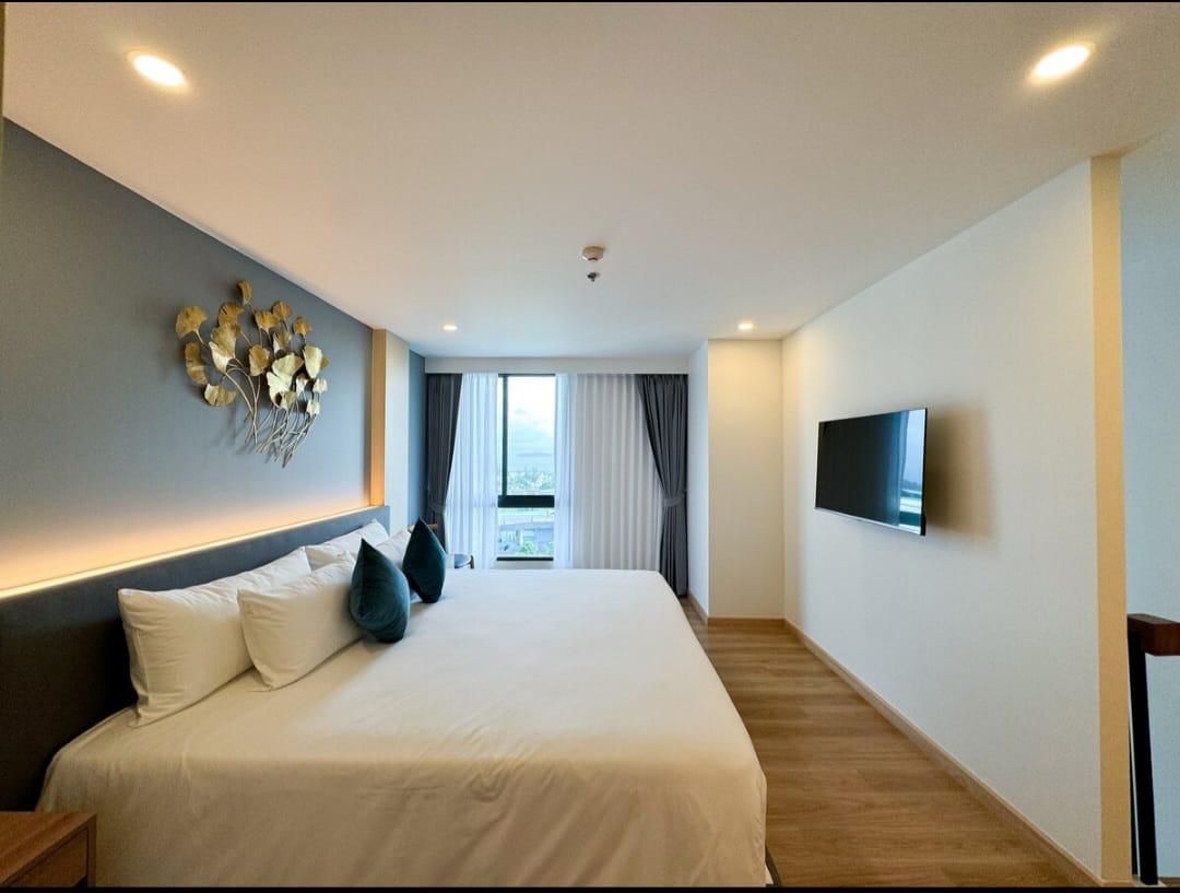 Bright hotel room with a large white bed, dark headboard and blue accent wall with metal leaf art.