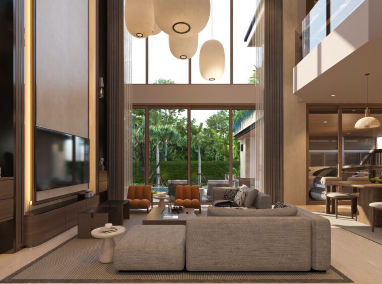 Spacious modern living room with gray sectional sofas, orange chairs, coffee tables, and large windows showing greenery outside.