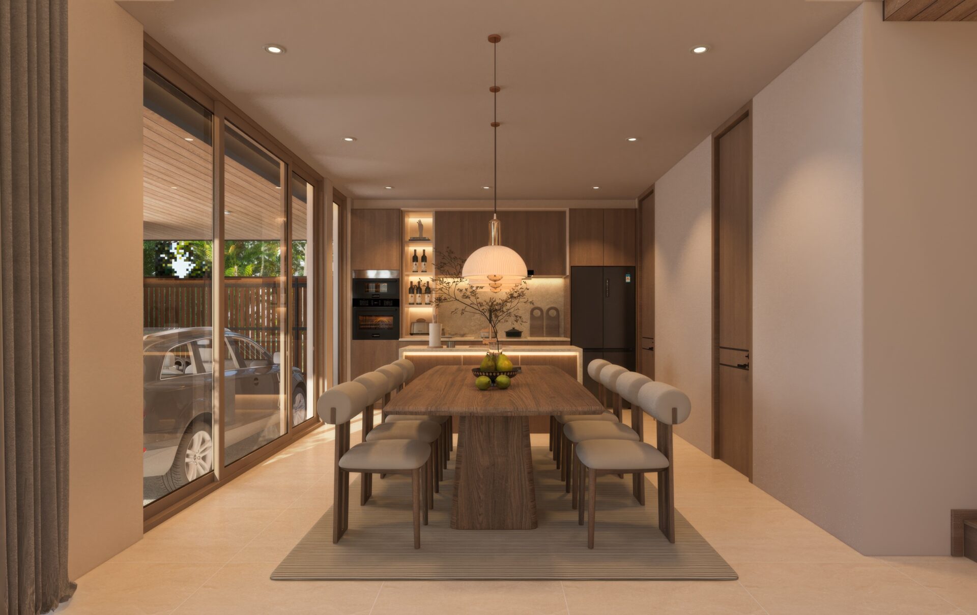 Open-plan dining kitchen with a long wooden table, white padded stools, and a pendant light, flanked by tall glass doors to a patio outside.