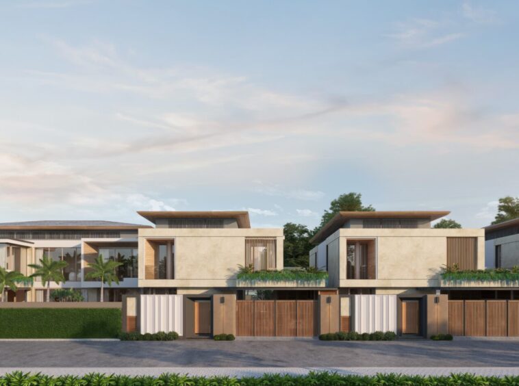 Row of contemporary two-story townhouses with beige stucco, wooden accents, balconies, and manicured front landscaping under a blue sky.