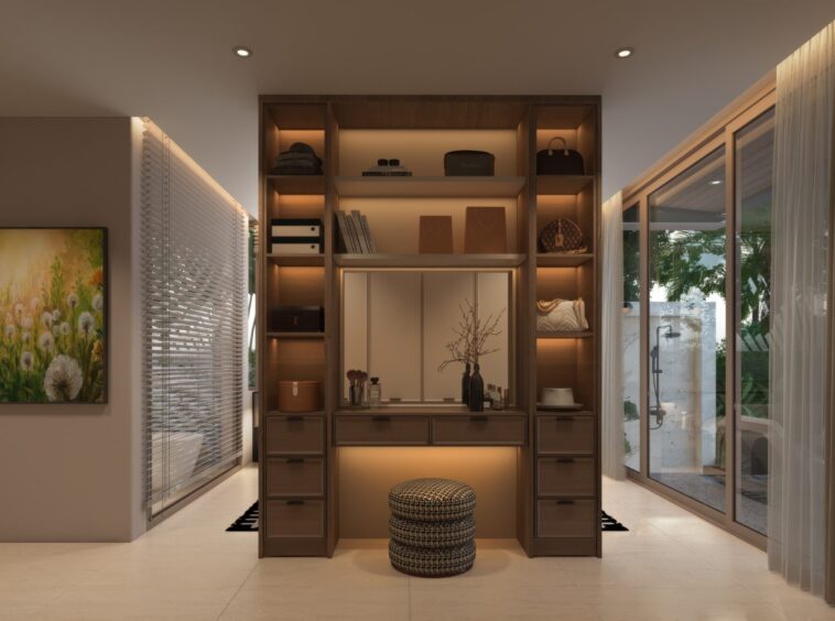Luxurious walk-in closet with warm backlit shelves, central cabinet, and woven ottomans in front of a glass door wall to the outdoors.