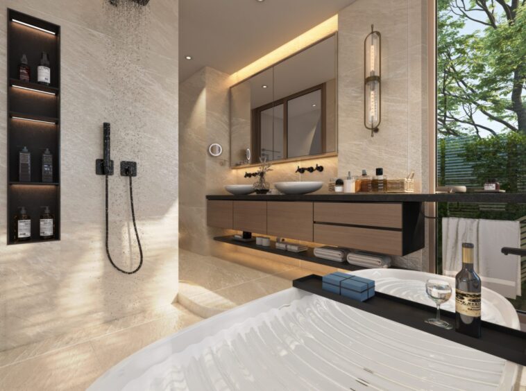 Modern beige marble bathroom with a rainfall shower, glass sink vanity, and a tub in the foreground holding a wine bottle and glass.