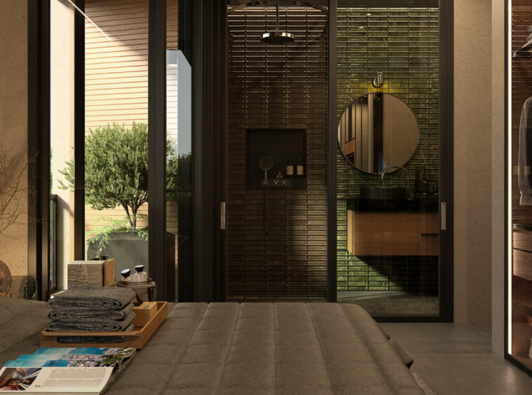 Bedroom with glass-walled en-suite: green tiled bathroom, round mirror, and wooden vanity seen through a doorway on the right side of the room.