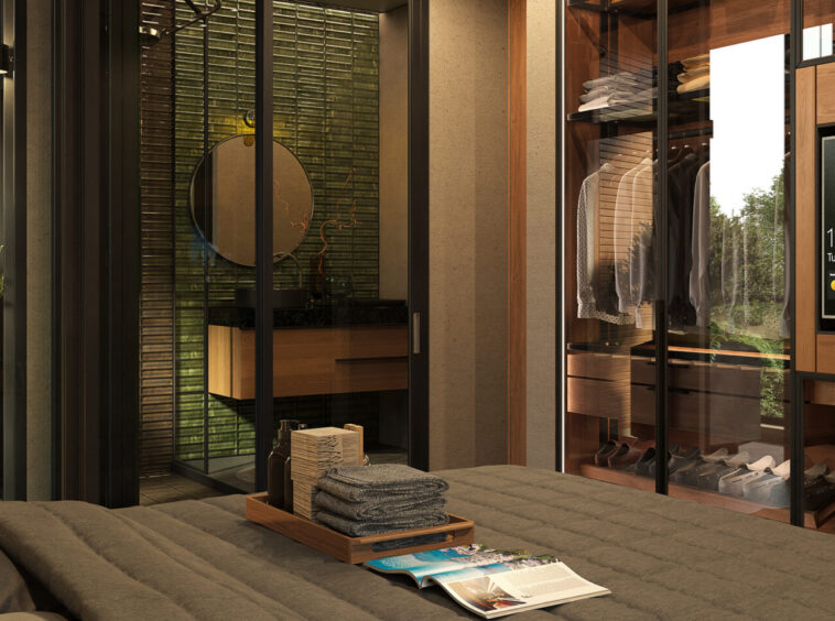 Luxurious bedroom with glass-walled walk-in closet, clothes on racks, and a large flat-screen TV displaying a landscape.