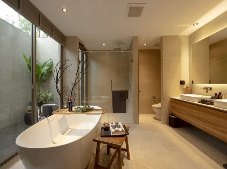 Luxurious beige-toned bathroom with a freestanding tub, glass shower, and double vanity