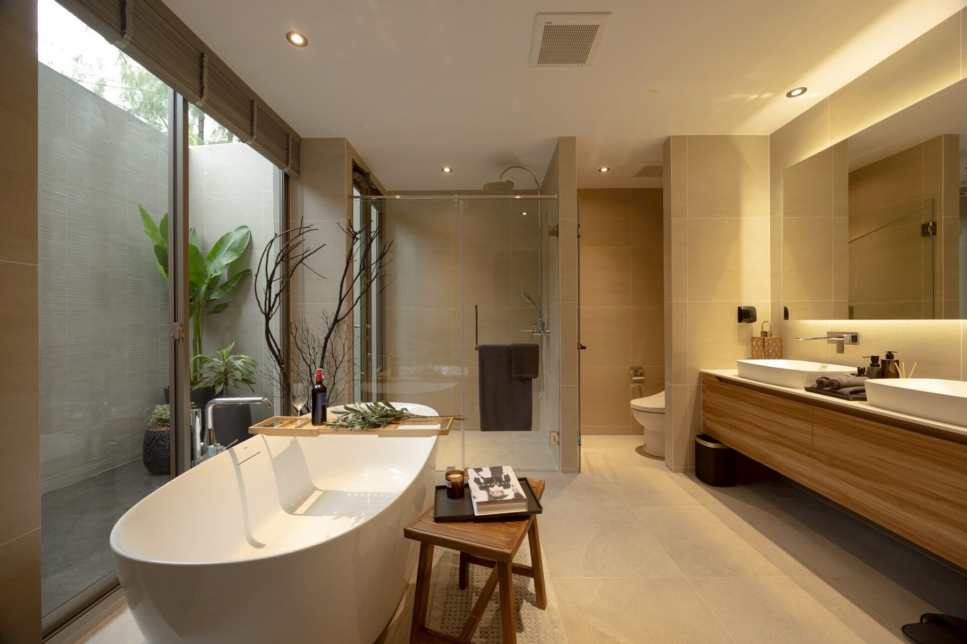 Luxurious beige-toned bathroom with a freestanding tub, glass shower, and double vanity