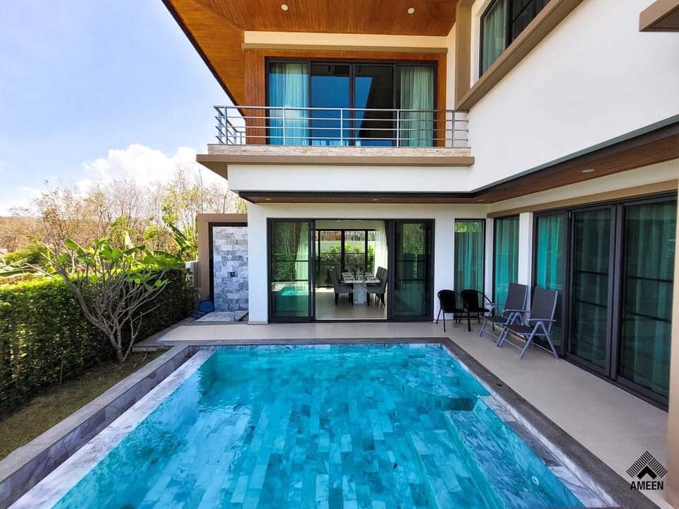 Modern two-story home with a rectangular pool, glass doors, and outdoor seating on a sunny backyard patio