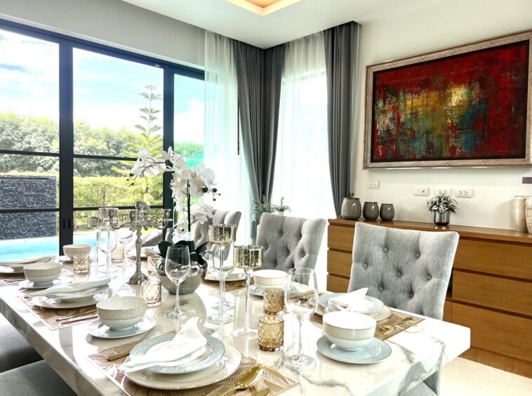 Elegant dining room with a marble table set for a formal meal, gray upholstered chairs, and a large abstract painting on the wall