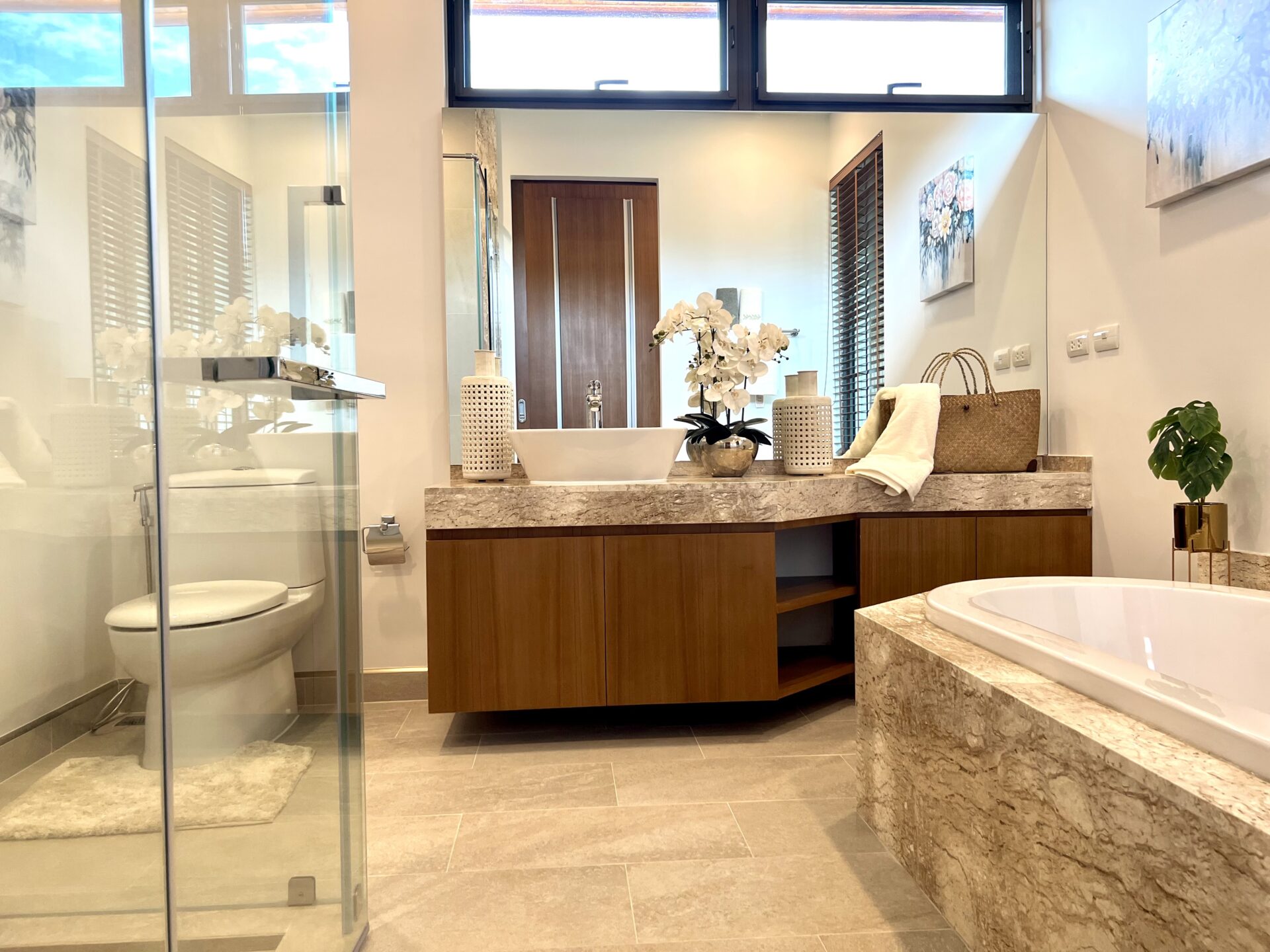 Modern bathroom with twin sinks on a marble countertop, and a glass shower enclosure on the left.