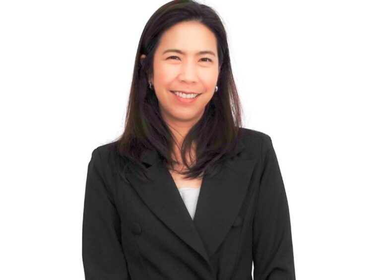 Professional headshot of a smiling woman in a black blazer against a white background.