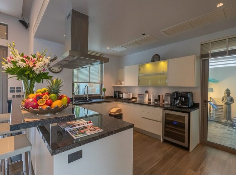 Modern kitchen with a dark granite island, stainless range hood, and a vibrant fruit bowl centerpiece; sliding glass door to the patio on the right.