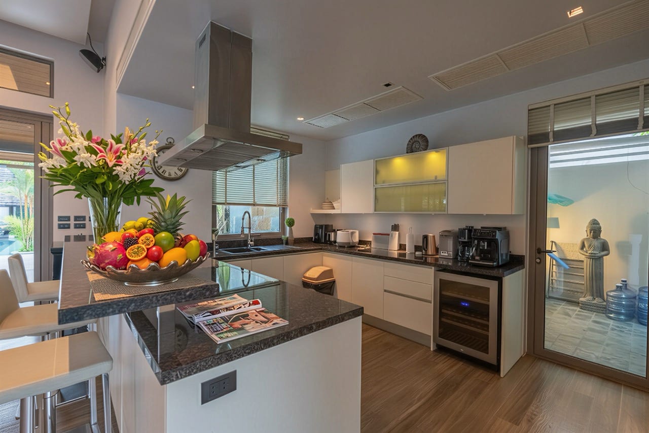 Modern kitchen with a dark granite island, stainless range hood, and a vibrant fruit bowl centerpiece; sliding glass door to the patio on the right.