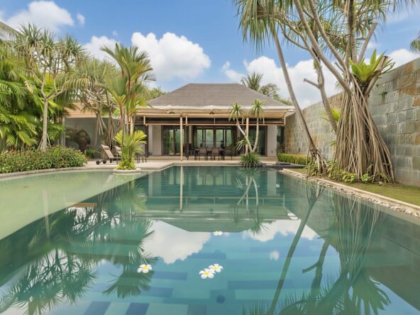 Luxurious tropical villa with a rectangular pool, palm trees, and a shaded outdoor dining area under a wooden pavilion.