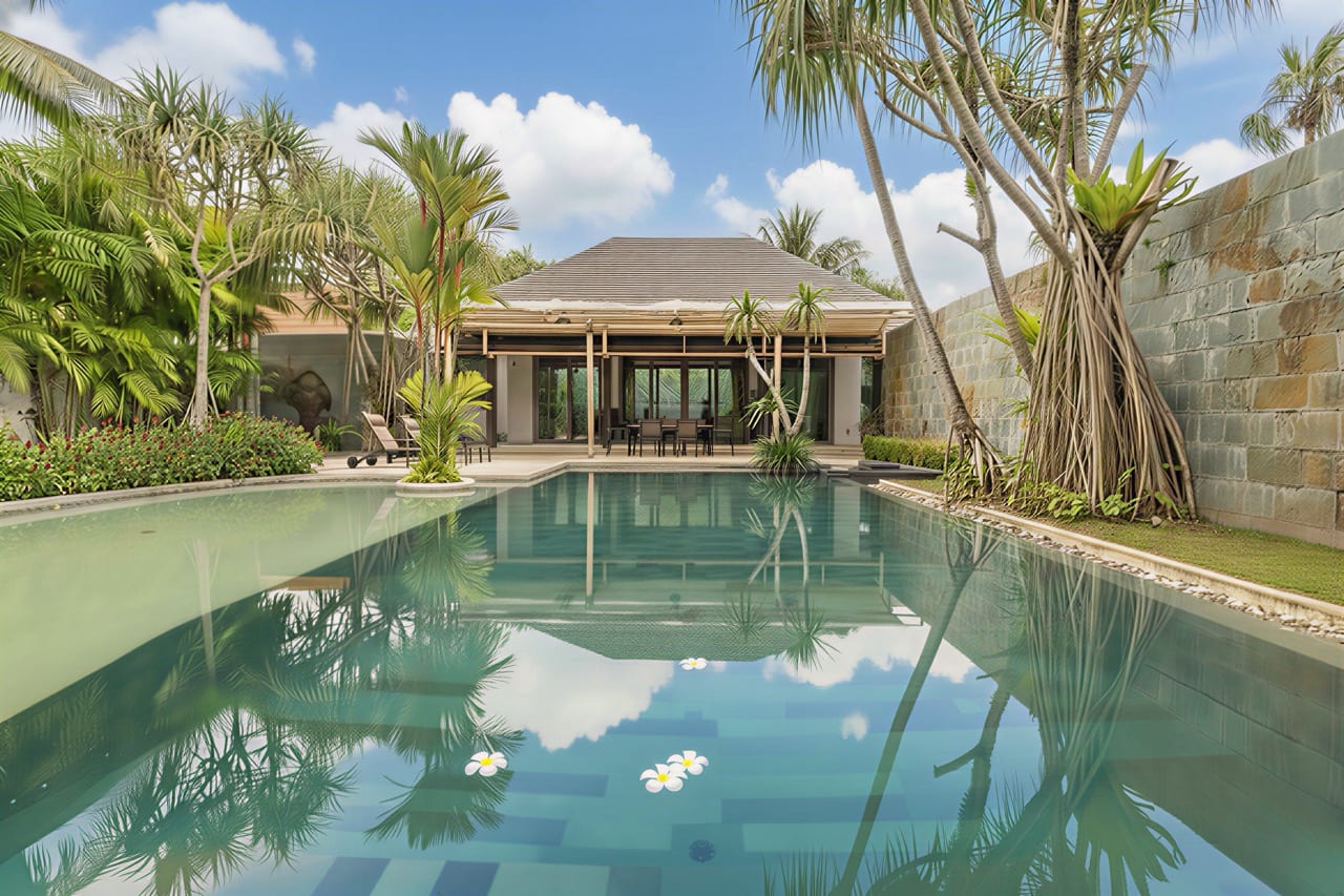 Luxurious tropical villa with a rectangular pool, palm trees, and a shaded outdoor dining area under a wooden pavilion.