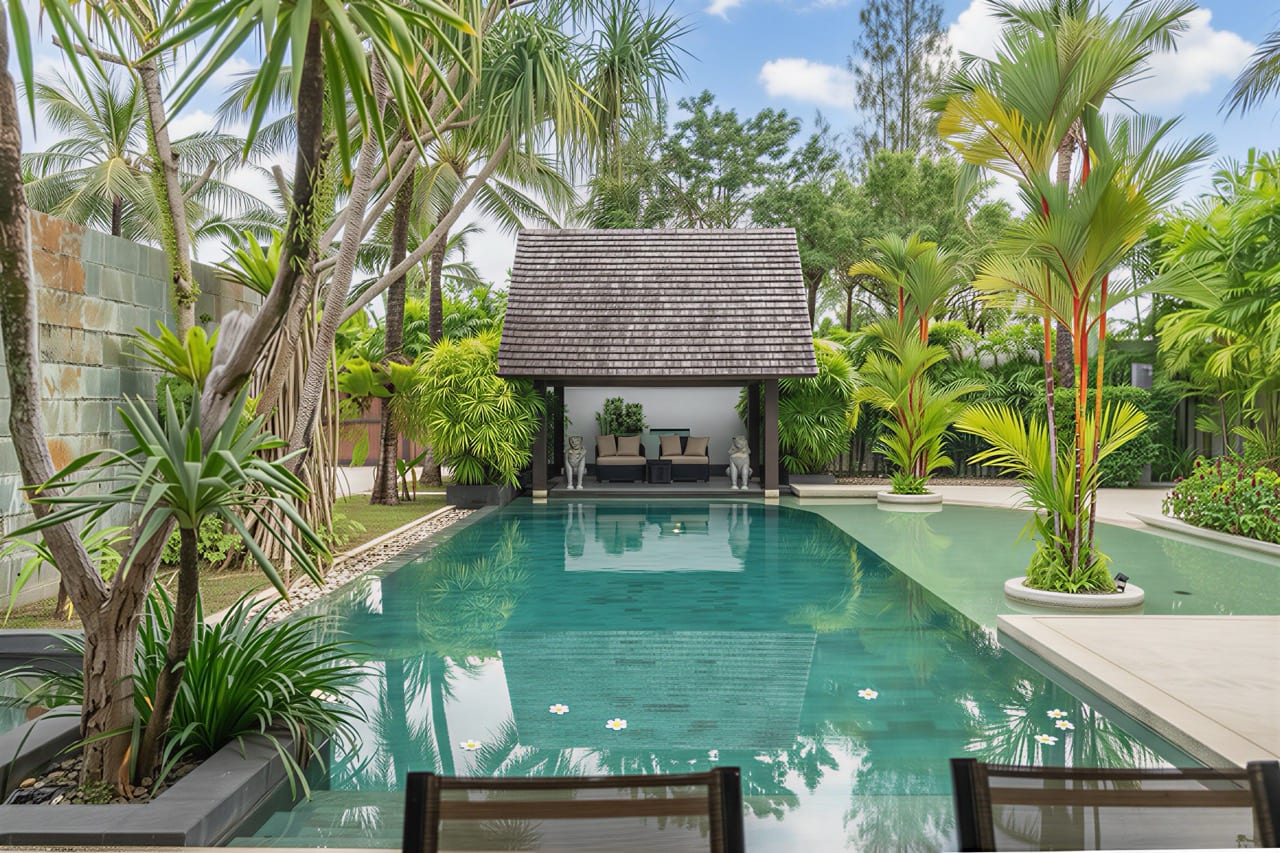 Luxurious backyard pool with palm trees, clear water, and a thatched-roof cabana with lounge seating at the far end.