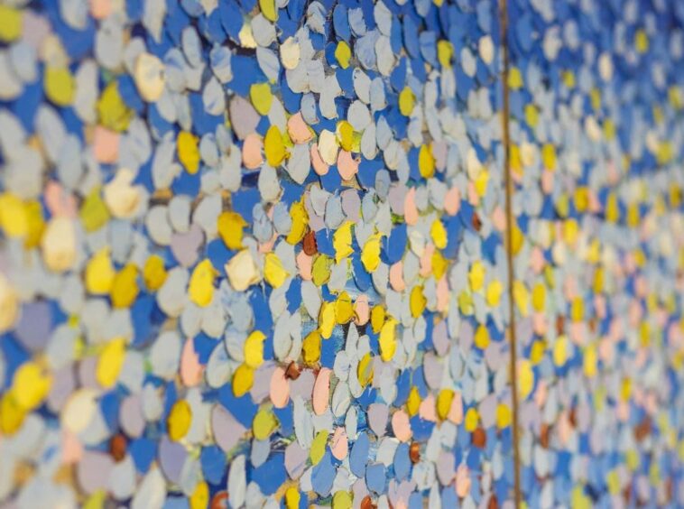 Colorful confetti-like petals densely covering a blue wall in a mural.