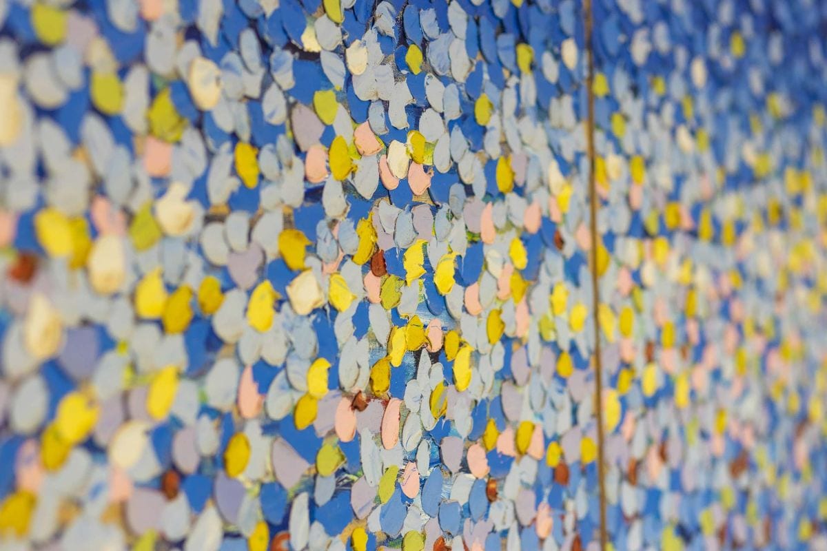 Colorful confetti-like petals densely covering a blue wall in a mural.