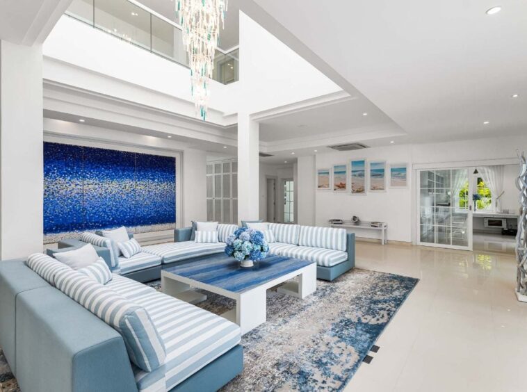 Spacious bright living room with a blue-and-white striped sectional, white coffee table, and a large blue abstract wall art.