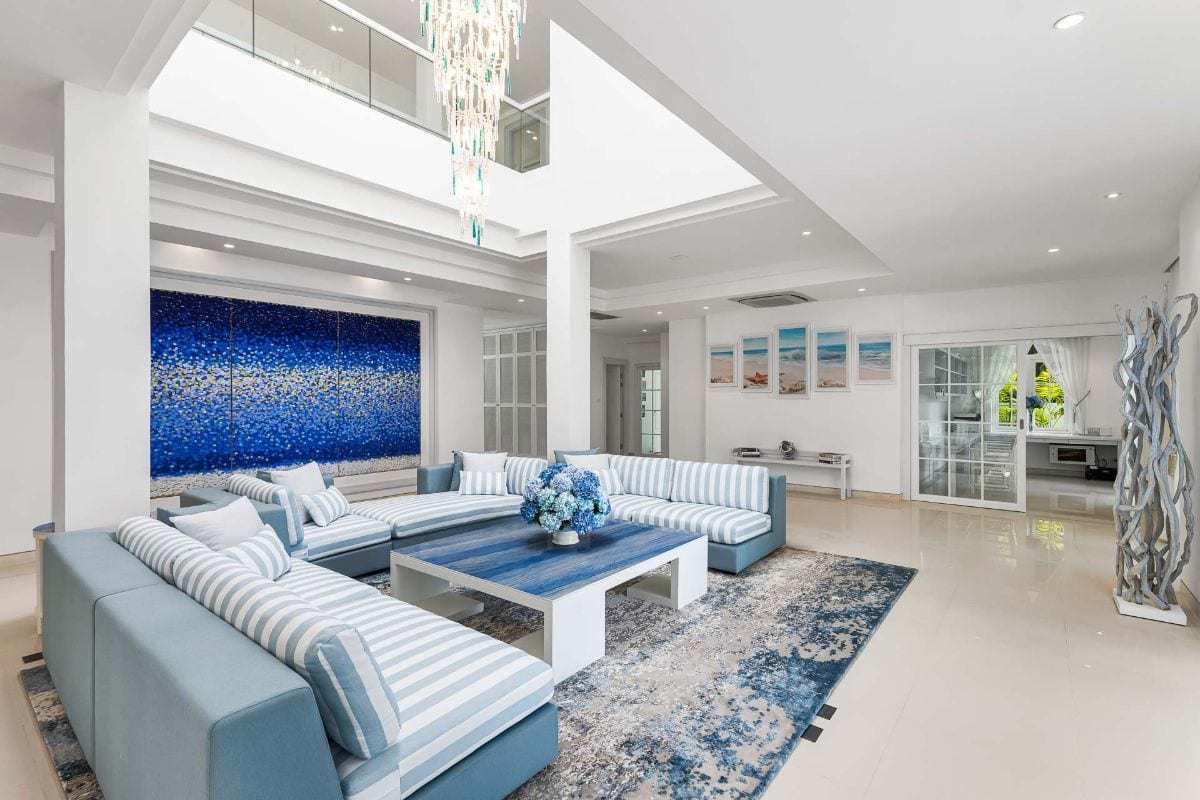 Spacious bright living room with a blue-and-white striped sectional, white coffee table, and a large blue abstract wall art.