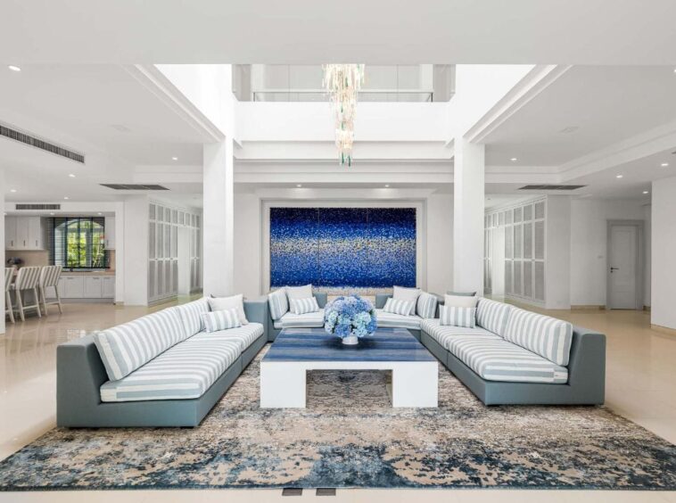 Coastal-inspired living room with a white-and-blue striped sectional around a blue coffee table and a large blue abstract painting.