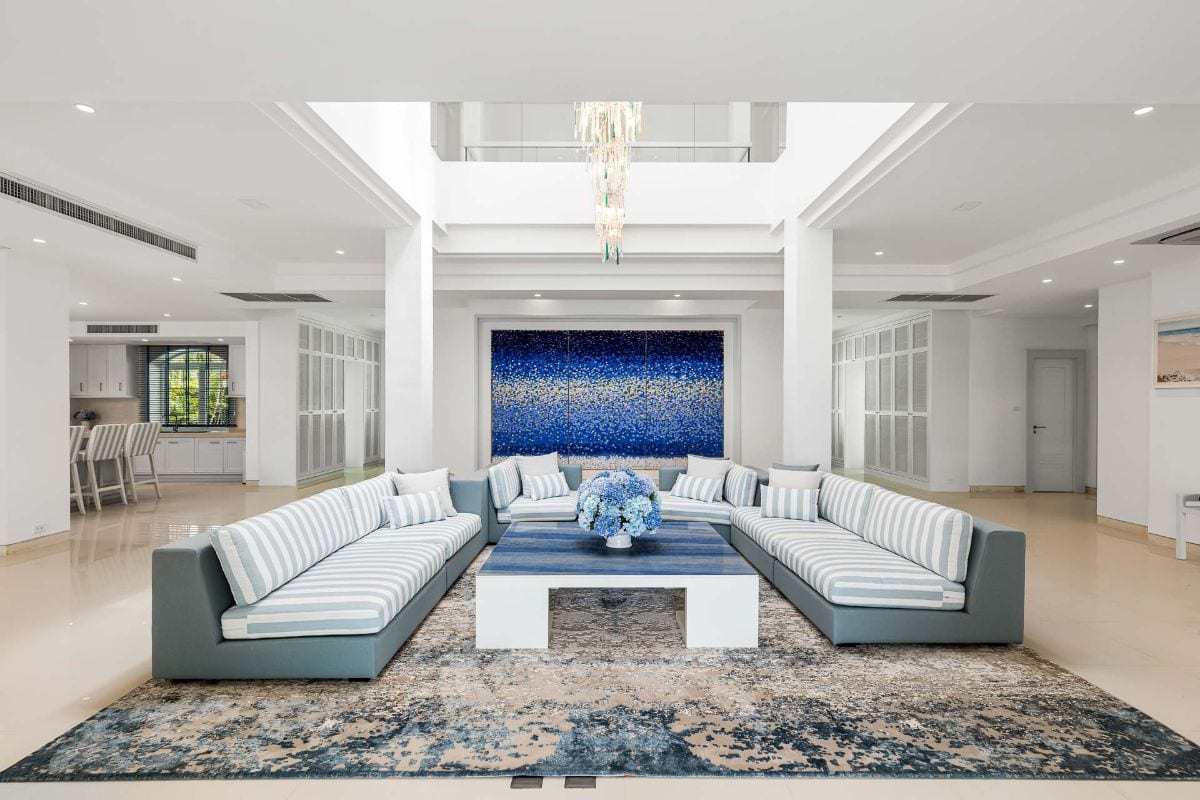 Coastal-inspired living room with a white-and-blue striped sectional around a blue coffee table and a large blue abstract painting.