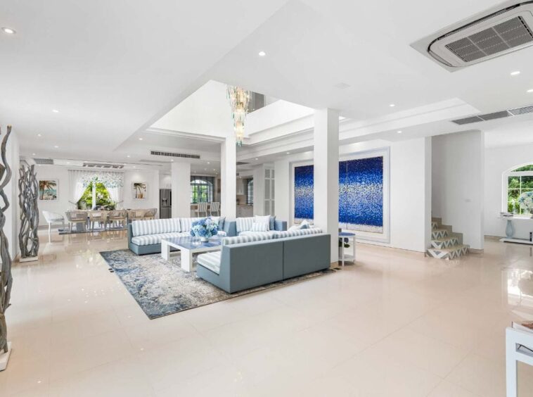 Bright open-plan living room with blue-striped sectional sofas, white coffee table, and a blue wall art piece.