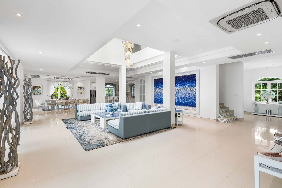 Bright open-plan living room with blue-striped sectional sofas, white coffee table, and a blue wall art piece.