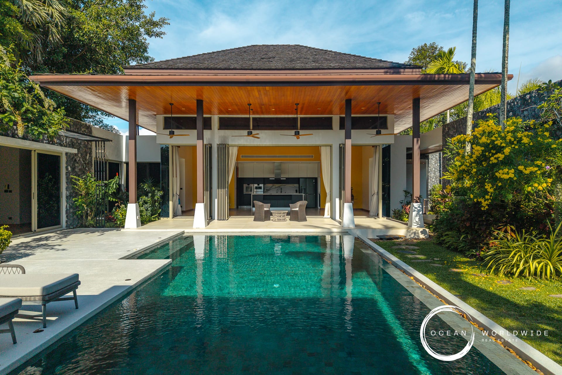 Resort-style villa with an outdoor pool, open living area, and tropical landscaping.
