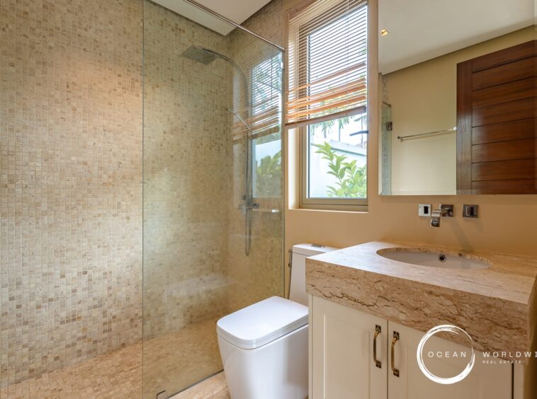 Modern bathroom with a glass-enclosed shower, beige mosaic tiles, and a white vanity.