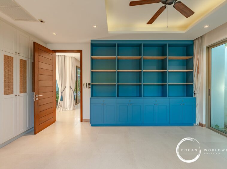 Blue built-in shelving unit with multiple open cubbies and matching lower cabinets in a bright, modern room.