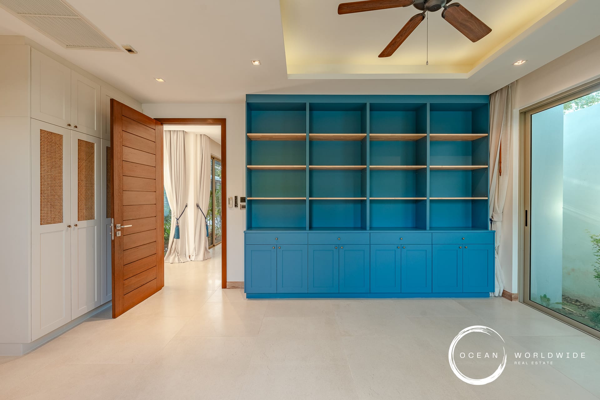 Blue built-in shelving unit with multiple open cubbies and matching lower cabinets in a bright, modern room.
