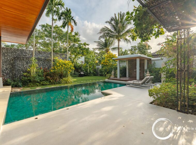 Poolside backyard with turquoise water, palm trees, and a shaded pavilion; lounge chairs on the deck nearby.