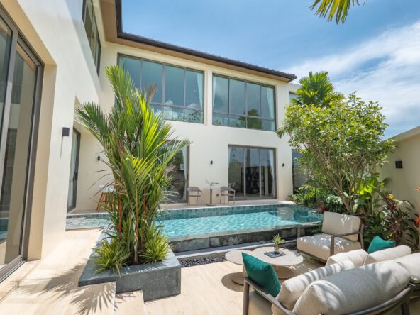 Modern two-story home courtyard with large glass doors, pool, and tropical plants under a blue sky