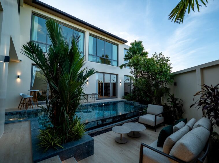 Modern two-story house with glass doors, pool, and tropical plants in a courtyard