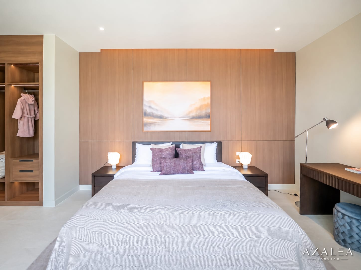 Modern bedroom with a large wood-paneled wall behind a king bed, framed landscape painting, and two lit bedside lamps on dark wood nightstands on either side.
