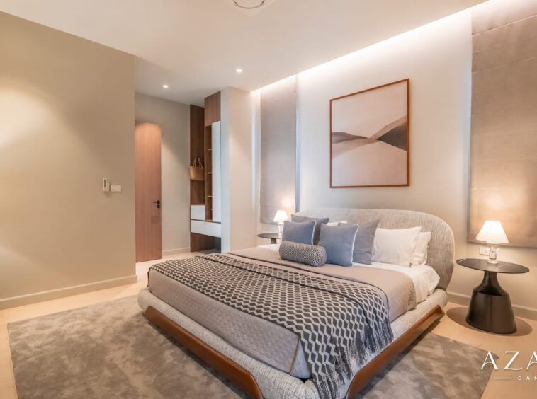 Luxurious hotel bedroom with king bed, neutral tones, and two round nightstands with lamps.