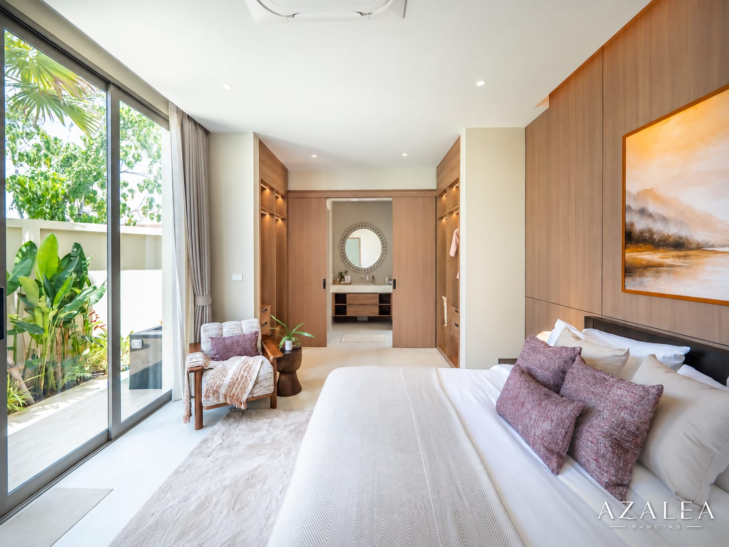 Luxurious hotel bedroom with a king bed, white linens, purple pillows, wood-paneled walls, and large glass doors to greenery outside.