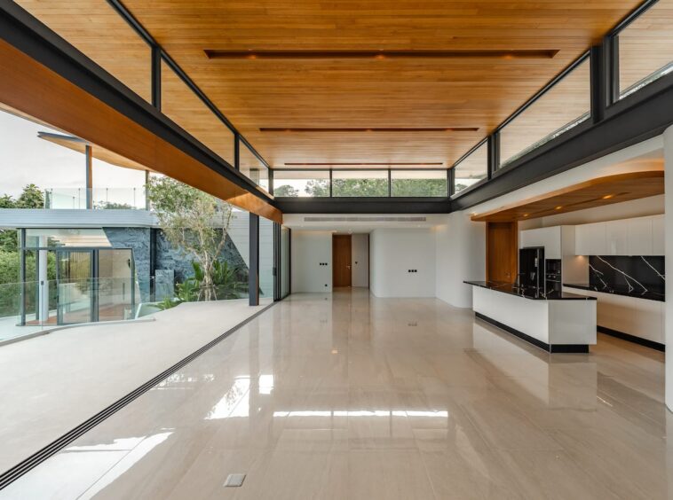 Open-concept living space with a white glossy floor, wood ceiling, black marble backsplash, and expansive glass walls.